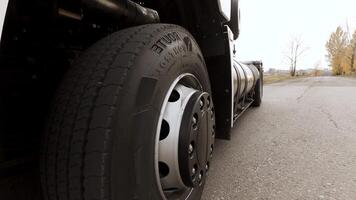 Close up of white freight truck passing by on highway. Scene. View on detail of truck wheel and tire rolling on dry freeway asphalt. video