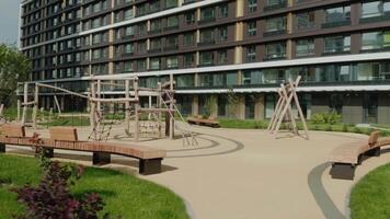 Summer landscape with empty modern playground in a new modern residential complex. . Children wooden playground with a multi storey house on the background. video