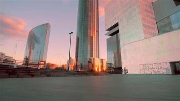 ein klein Platz im Vorderseite von ein modern Glas Fassade Geschäft Center mit ein golden Sonnenuntergang reflektiert im Fenster. . Konzept von modern die Architektur. video