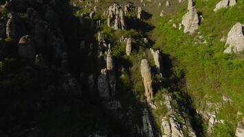 sten pelare på sluttningar av berg. skott. skön flyg på klippig sluttningar med erosion och grön träd. mängd av klippig formationer på sluttningar av grön bergen video