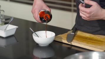 Close-up of chef cooking with soy sauce. Art. Cook adds soy sauce to dressing and mixes it in bowl. Mixing sauce in dish bowl video