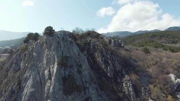 Rocky ridge on background of mountain landscape on sunny day. Shot. Small rocky mountain on background of mountain horizon on clear day. Top view of rocky slope with cross video