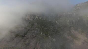 volador mediante bajo nubes a montañas. disparo. encantador vuelo mediante bajo nubes a rocoso montañas. Mañana nubes tenido descendió en denso féretro a alto montañas video