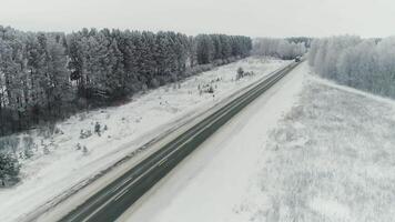 Antenne Aussicht von ein b Fracht LKW Fahren Nieder ein Autobahn Laufen entlang ein Eisenbahn auf ein klar Winter Tag. Ladung Lastwagen Transport Behälter über das robust schneebedeckt Wüste im Utah. video