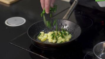 avvicinamento di cucinare frittura patate e verdi. arte. professionale capocuoco prepara semplice piatti con patate e fagioli. cucinare mette verde fagiolo baccelli nel fritte patate video