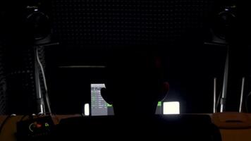 Rückseite Aussicht von männlich Audio- Ingenieur Arbeiten im Musik- Aufzeichnung Studio im Vorderseite von Computer. hdr. Musik- Schöpfer beim Arbeit im ein dunkel Studio. video