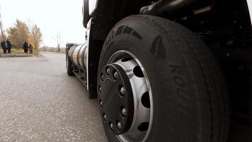 Close up of white freight truck passing by on highway. Scene. View on detail of truck wheel and tire rolling on dry freeway asphalt. video