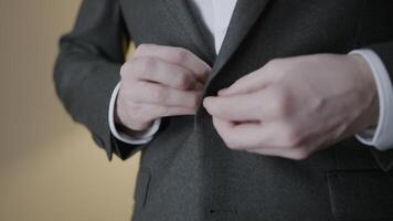 Close-up of gentleman adjusting suit jacket. Action. Attractive man adjusts tuxedo before celebration. Gentleman straightens jacket and buttons it up video