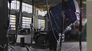 Rear view of a professional mechanic using an air wrench for the truck repair. Scene. Details or working process of a service center. video