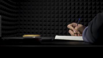 concept de l'écriture de chansons, côté vue de une homme l'écriture Paroles dans une professionnel la musique studio. hdr. processus de création une chanson par le auteur, musicien l'écriture texte sur une feuille de papier. video