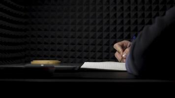 Concept of songwriting, side view of a man writing lyrics in a professional music studio. HDR. Process of creating a song by the author, musician writing text on a sheet of paper. video