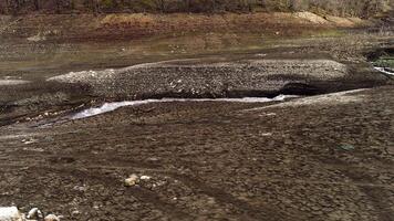 aereo al di sopra di un' stretto ruscello con forte attuale su asciutto terra. sparo. largo fiume divennero un' acqua ruscello perché di siccità, concetto di ecologia. video