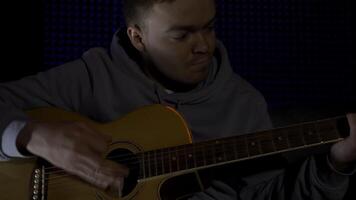 homme en jouant guitare, enregistrement une chanson dans professionnel du son studio. hdr. portrait de une Jeune homme en jouant acoustique guitare dans une foncé chambre. video