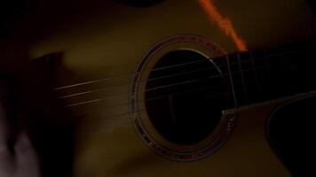 hombre jugando acústico guitarra en un oscuro habitación, concepto de música y creatividad. hdr. cerca arriba ver de masculino dedos jugando ritmo solo con un mediador. video