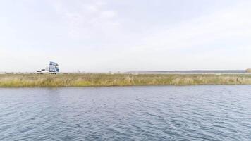 caméra en volant le long de le ondulé rivière avec une conduite un camion sur le Contexte. scène. aérien vue de une camion conduite le long de le des champs et une rivière dans une campagne zone. video