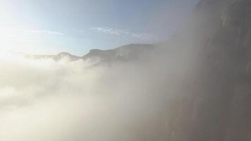 Beautiful sunrise with mountain scenery and low clouds. Shot. Spectacular flight over clouds at rocky mountain slopes at dawn. Aerial landscape with low clouds near rocky mountains video