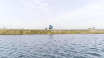 camera vliegend langs de golfde rivier- met een het rijden vrachtauto Aan de achtergrond. tafereel. antenne visie van een vrachtwagen het rijden langs de velden en een rivier- in een platteland Oppervlakte. video