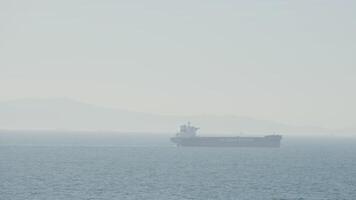 nave su nebbioso spiaggia con sole. azione. singolo nave nel nebbioso mare su sfondo di costa. nebbioso giorno a mare con solitario nave via costa video