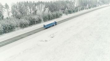 camión conducir a lo largo el la carretera mediante el invierno bosque. escena. aéreo ver en coche conducción en invierno, la carretera rodeado con hermosa bosque cubierto en nieve video