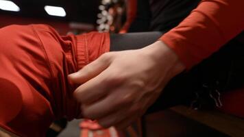 Hockey player putting on uniform. Action. Close-up of athlete putting on uniform and protection on feet. Hockey player puts on uniform in locker room video