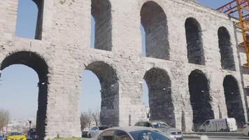 Aqueduct in modern city. Action. Highway passing under historic aqueduct. Ancient architectural structure of aqueduct is tourist attraction in Istanbul video