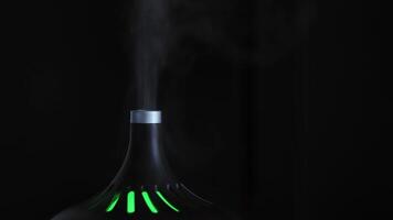 cerca arriba de un elegante aire humidificador con Luz de noche aislado en negro antecedentes. concepto. concepto de comodidad y hogar estilo, blanco vapor creciente arriba. video