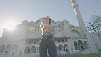 schön Frau posieren auf Hintergrund von Tempel. Aktion. glücklich Frau Tänze draußen Moschee auf sonnig Tag. schön Frau kreisen in der Nähe von Moschee auf Hintergrund von Sonne Strahlen video