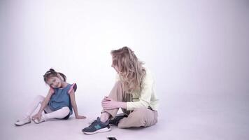 Young blond mother with her daughter playing and spend time together. Clip. Concept of family and parenthood, mom and girl at a photo studio. video