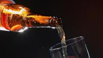 Close up of pouring beer from the glass brown bottle into the glass. . Pouring alcoholic drink isolated on black background, concept of party. video