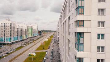 aéreo Visão do uma moderno residencial edifícios e uma cidade rua com dirigindo carros. . recentemente construído colorida casas em nublado céu fundo. video