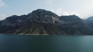 natürlich Landschaft mit ein Türkis Wasser Reservoir und ein enorm Berg. Aktion. Ruhe Blau Fluss und ein hoch Hügel auf Blau Himmel Hintergrund. video