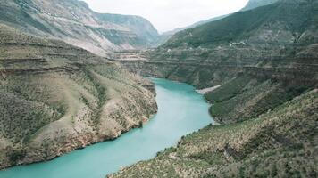 aéreo ver de montañoso región con fluido amplio calma río. acción. asombroso salvaje paisaje con alto acantilados, río, y nublado cielo en un verano día. video