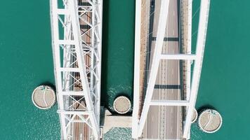 antenne top visie van de Krim brug Aan turkoois water achtergrond. schot. passagier auto's het rijden mooi wit brug bovenstaand kerch zeestraat. video