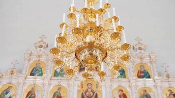 Christian orthodoxe église intérieur dans blanc et d'or couleurs. . lustre avec artificiel bougies dans le temple avec iconostase. video