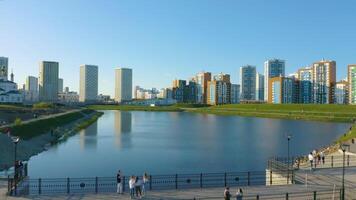 Ekaterinburg, Ryssland, en damm med en bro i en ny parkera. . antenn se av en skön stad distrikt med färgrik hög stiga byggnader på blå himmel bakgrund. video