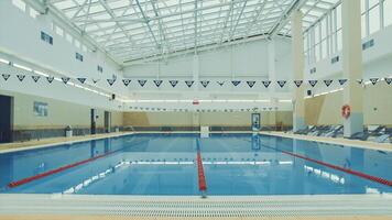 View inside of a swimming pool at the sports complex. . Beautiful swimming pool with glass ceiling and calm water. video