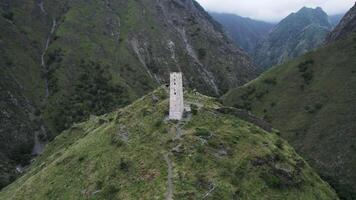 aéreo Visão do a antigo velório construção tsoy pede, a checheno república, Rússia. Ação. branco torre em a topo do uma verde Colina cercado de montanhas. video