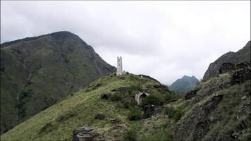 geweldig antenne visie groen bergen en oude steen gebouw Aan de top van een heuvel. actie. oud steenachtig wit verlaten toren gebouwd Aan een berg piek. video