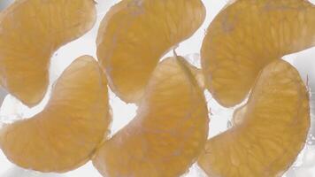 peeled halved tangerine on white backgroundConcept of healthy diet and vitamins. Stock footage. Close up bottom view of peeled tangerine slices lying on glass transparent surface that is being filled video