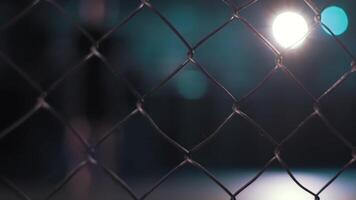 Close up of chain link fence on dark blurred background with shining lamp. . Metal lattice inside the building, grunge style. video