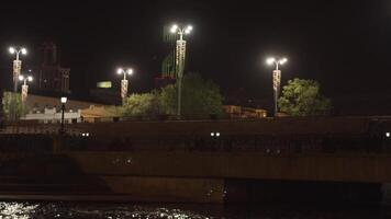 de dam van de ekaterinburg stad met lantaarns en de iset rivier, Rusland. voorraad filmmateriaal. een brug bovenstaand de rive Bij nacht Aan zwart lucht achtergrond. video