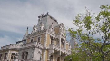 mooi facade van Europese paleis Aan achtergrond van bomen en lucht. actie. geel paleis in Europese stijl met tuin. massandra paleis in Krim video