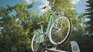 Bottom view of a light turquoise retro bicycle on a stand outdoors on a summer sunny day. . Old fashioned bicycle on the background of green trees. video