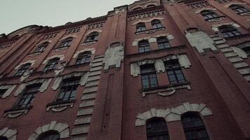 Bottom view of classic old fashioned red brick building, concept of architecture. . Beautiful ancient house on grey sky background. video