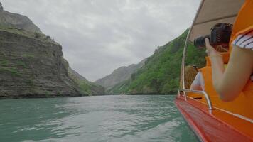 utflykt båt resa på berg flod. handling. turister i västar simma på båt på flod med se av rocks. båt Flott på turkos flod med sten massiv i molnig väder video