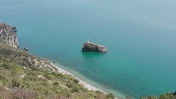 Haut vue de traverser sur côtier rock. action. traverser est situé sur rocheux récif près mer côte. sacré île avec traverser près côte. magnifique vue de rocheux côte avec sacré île dans bleu mer video