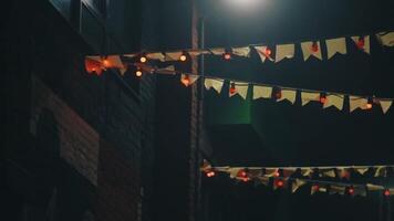 pequeno bandeiras festão, chinês decoração contra noite céu e prédio. . lindo bandeiras e lâmpadas guirlandas suspensão em a corda 1 de um. video