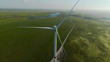 Flying at wind generators. Shot. Beautiful landscape with wind power generators on green fields. Windmills generate energy from the wind in fields. Wind energy video