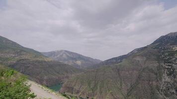 Beautiful river in rocky mountains on background of cloudy sky. Action. Turquoise river among rocky mountains in cloudy weather. Beautiful nature of rocky mountains and clear river video