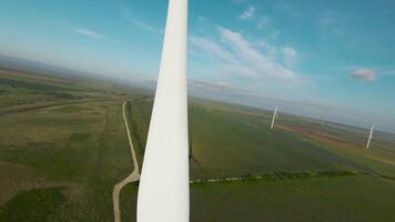 Electric mill wing. Shot. Top view of landscape with wind farms and generators on background of green fields. Windmills on background of horizon with fields and blue sky. Wind energy video